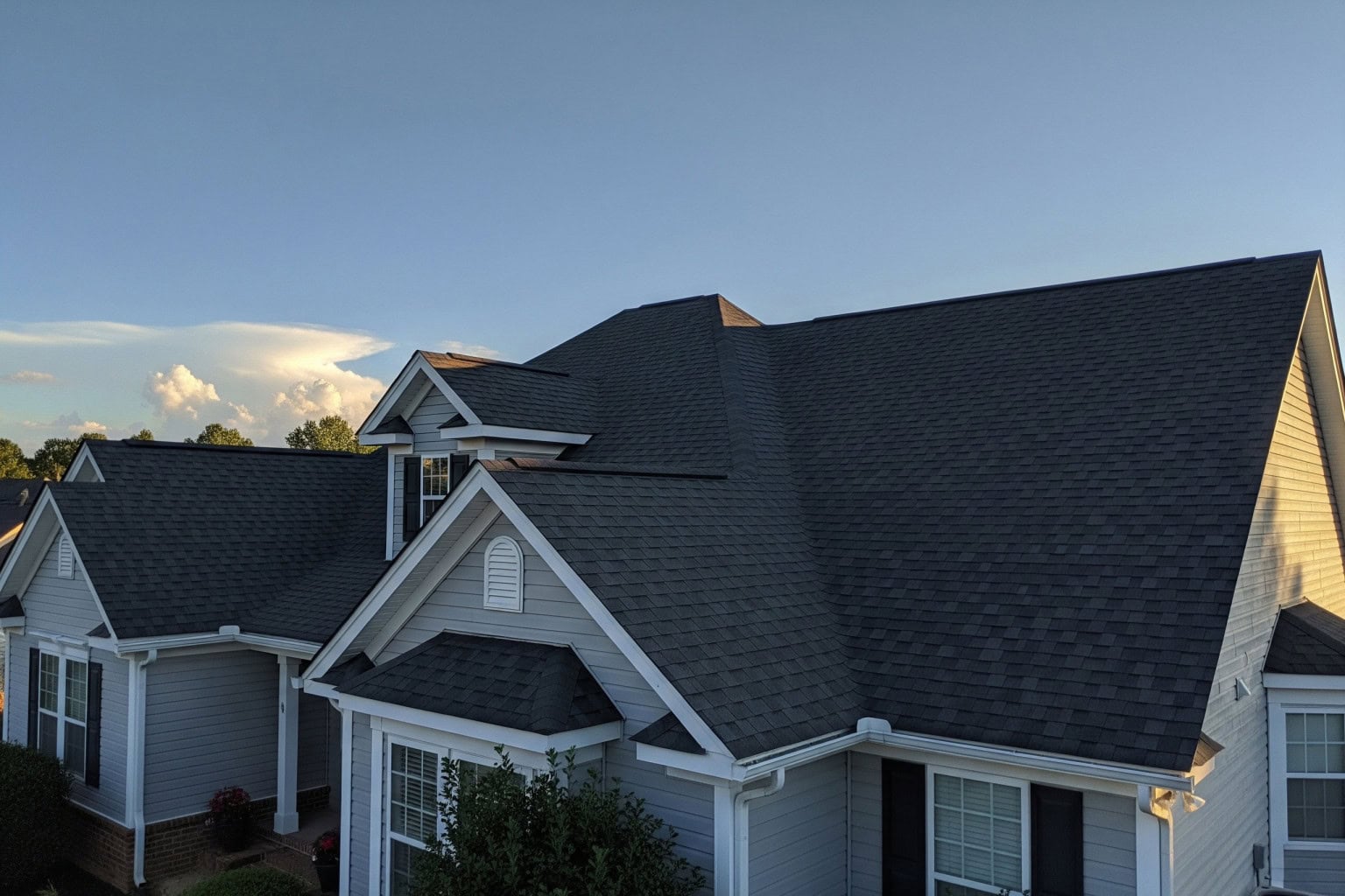 Spartanburg, SC home with repaired asphalt-shingle roof Repaired asphalt-shingle roof on a large Spartanburg, SC home at dusk.